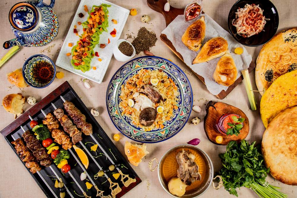 A spread of Uzbek dishes including plov, shashlik, samsa and fresh bread