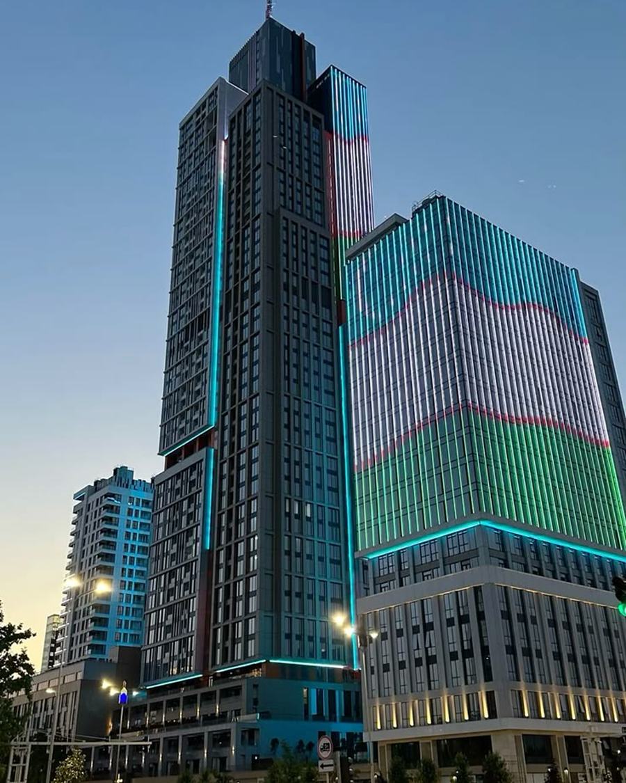 The illuminated towers of Tashkent City lit in the colours of the Uzbek flag at dusk